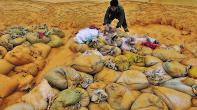 Un lavoratore setaccia sacchi di materiale alla ricerca di terre rare in una miniera di Nancheng, in Cina