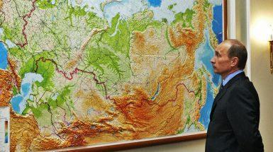 Vladimir Putin di fronte a una mappa murale della Russia