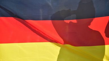 A silhouette of a supporter of the German national football team is pictured behind the German national flag at the end of a public viewing event at the Fanmeile in Berlin to watch the Russia 2018 World Cup Group F football match between South Korea and Germany where the reigning world champions were defeated 0-2 on June 27, 2018. (Photo by John MACDOUGALL / AFP)        (Photo credit should read JOHN MACDOUGALL/AFP/Getty Images)
