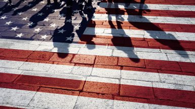 Shadows of group of people walking through the streets with painted Usa flag on the floor. Concept political relations with neighbors.